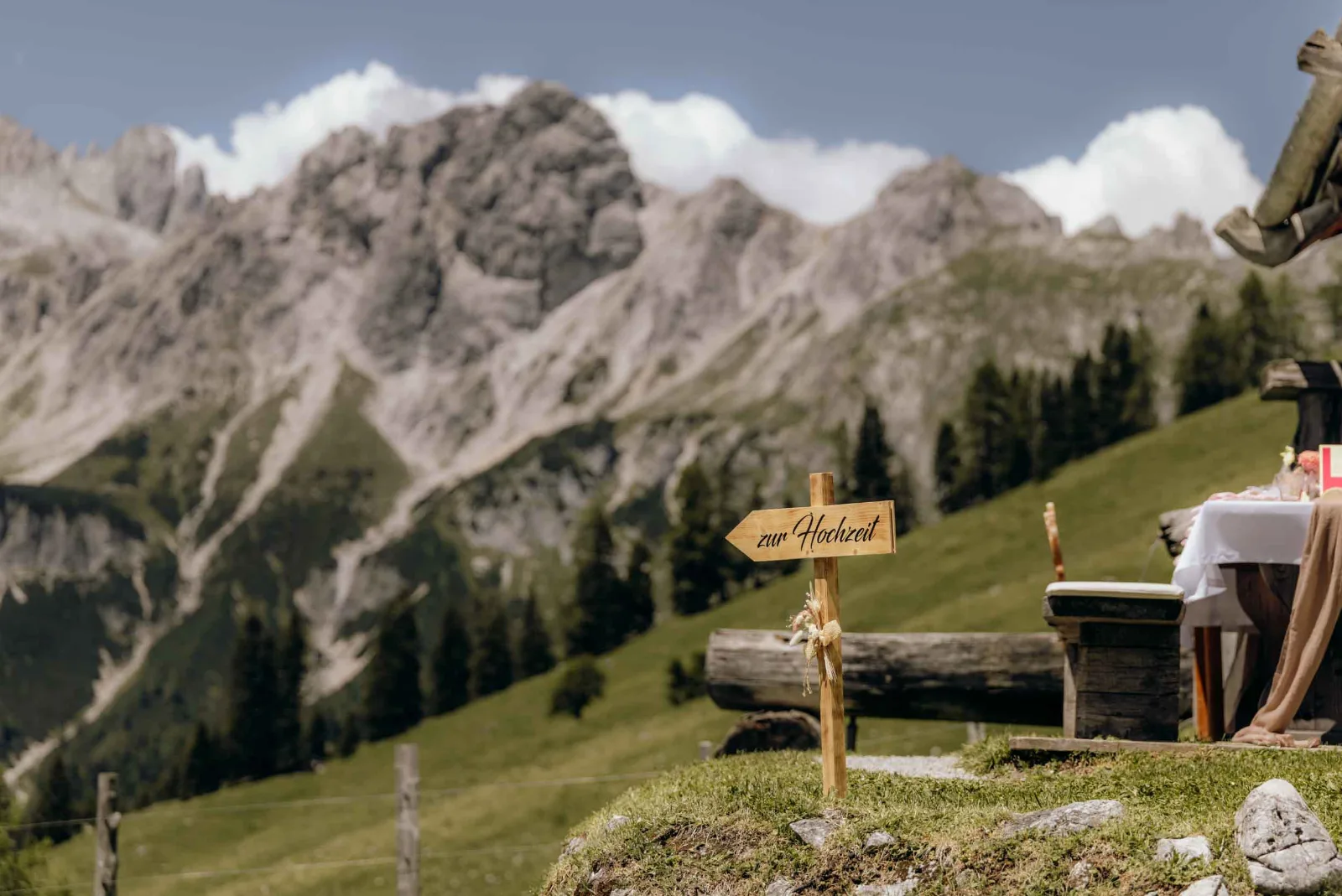 Ein Wegweiser zur Hochzeit führt als Hochzeitsfotograf München zu einem festlich gedeckten Tisch vor der Kulisse der Berge.