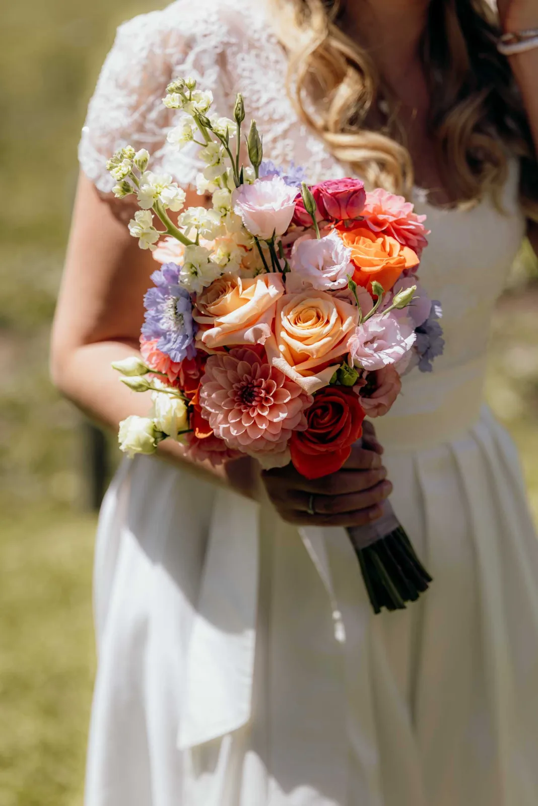 Als Hochzeitsfotograf München begleite ich diese Hochzeit und halte den farbenfrohen Brautstrauß fest, während die Braut ihr weißes Kleid trägt.