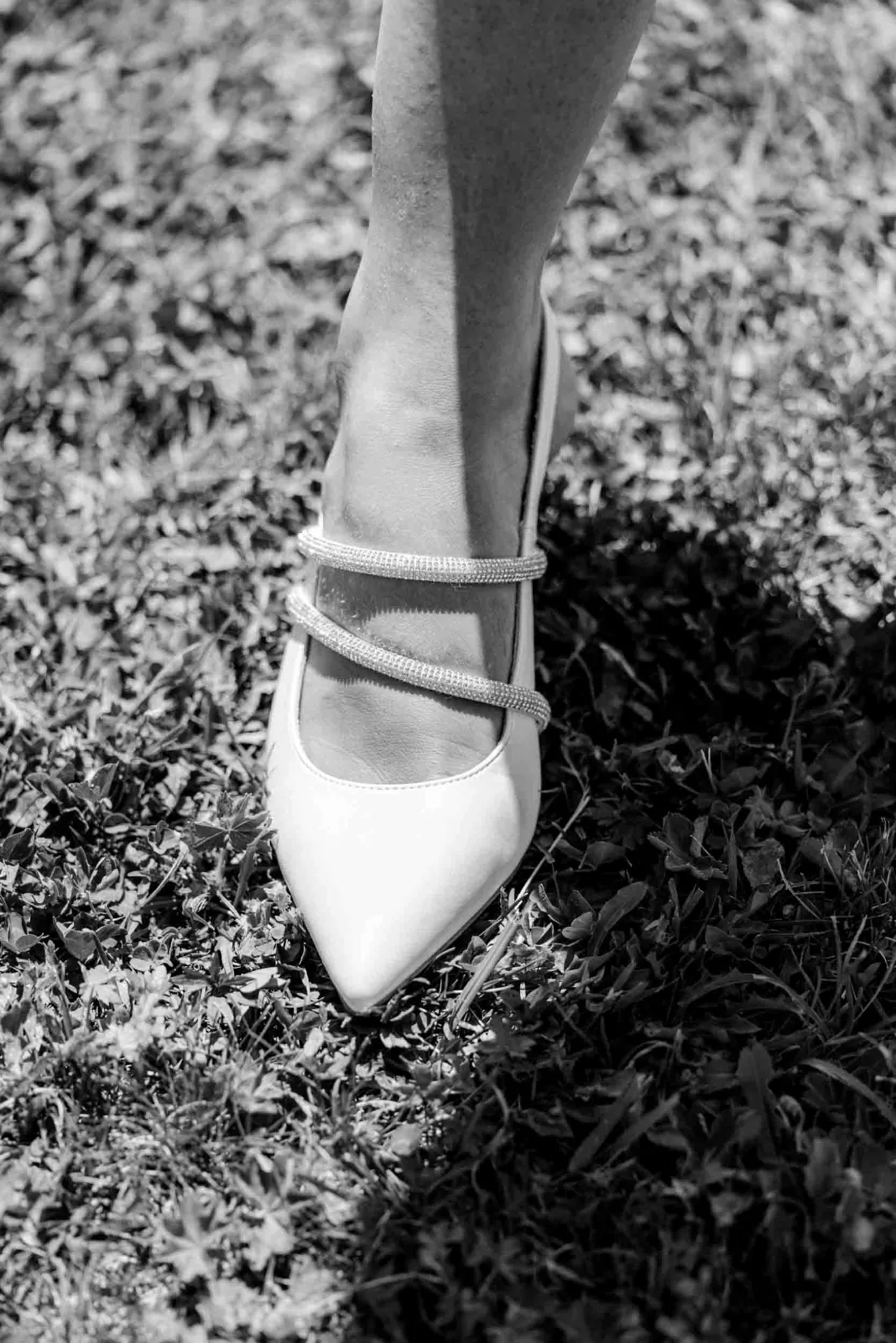 Ein mit Steinen besetzter Brautschuh steht auf dem Gras während einer Begleitung von MOKATI als Hochzeitsfotograf München.