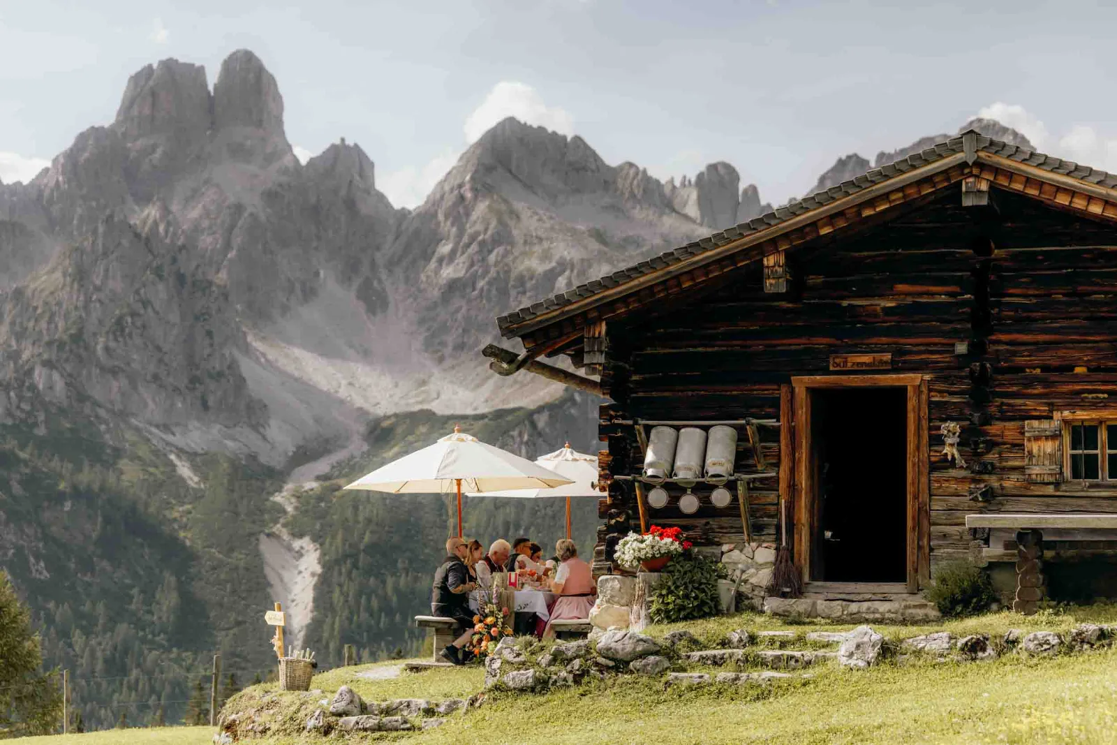 Ein Paar beim gemeinsamen Essen vor der Löckwaldhütte, das ich als Hochzeitsfotograf München bei einem Elopement in Filzmoos begleite.